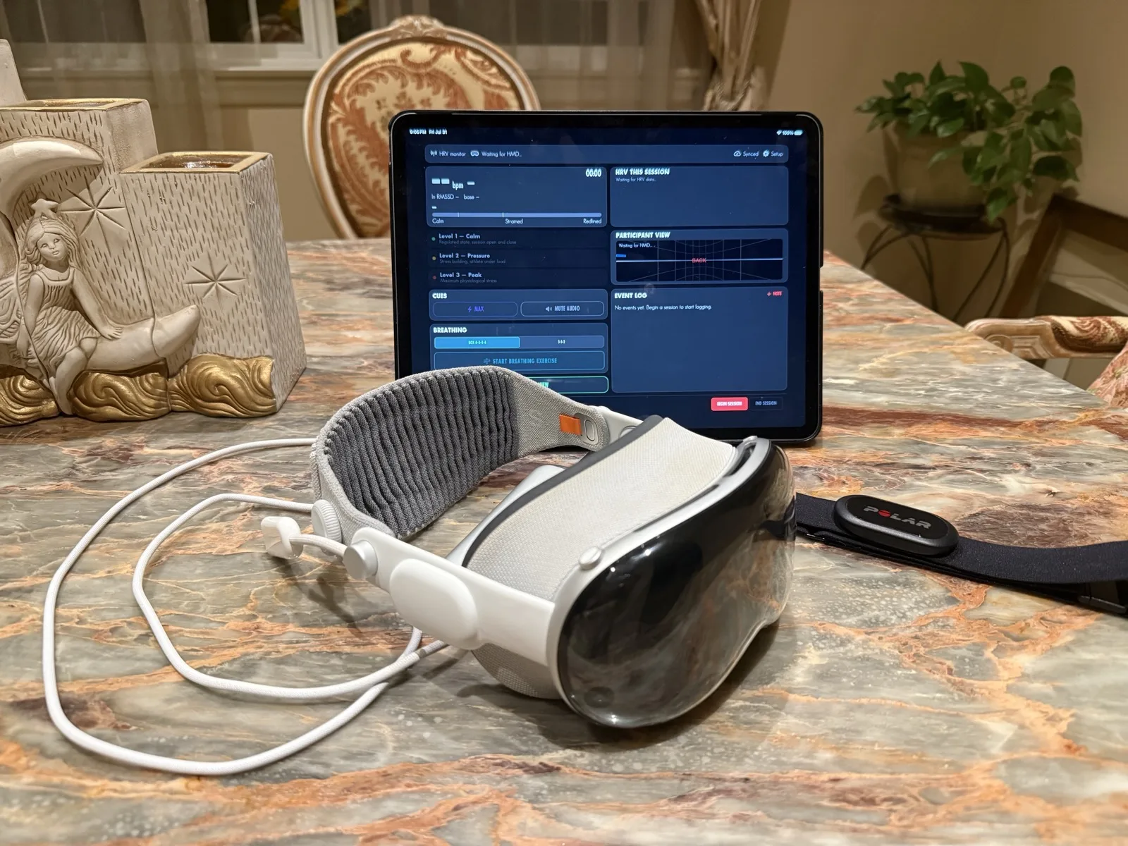 The ImmerSIT kit laid out on a table: an Apple Vision Pro headset, a Polar heart-rate chest strap, and an iPad running the coach's console waiting to connect to the headset